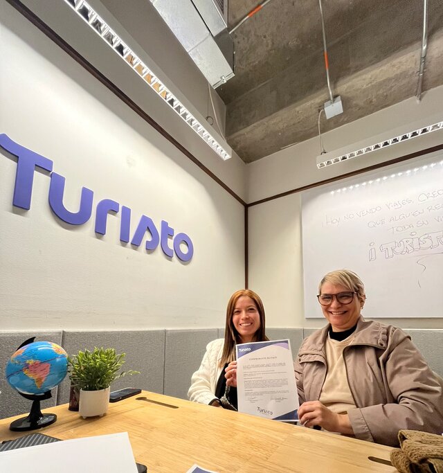 Clienta de Turisto recibiendo su comprobante de pago en la oficina